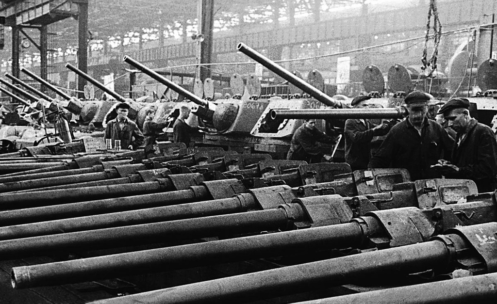 Кировский завод Наркомата танковой промышленности. Цех сборки. Участок монтажа орудий, 1943 - 1945, г. Челябинск. Первый экспериментальный танк на заводе был выпущен 30 декабря 1940 года. Массовое производство танков и САУ началось в ноябре 1941 года, когда на площадках завода разместили оборудование ленинградского Кировского, Харьковского и других тракторных заводов.&nbsp;Кировский завод Наркомата танковой промышленности – ныне Челябинский тракторный завод.