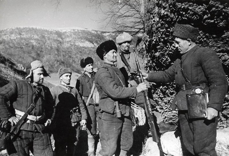 Перед боем. Комиссар партизанского отряда вручает винтовку новому бойцу, 1942 год. Выставка «Партизаны» с этой фотографией.
