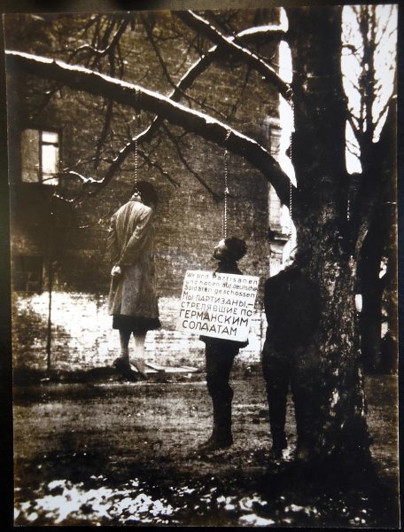 Публичная казнь на улице Карла Маркса в Минске, 26 октября 1941, Белорусская ССР, г. Минск. Сестра и брат Надежда и Петр Янушкевичи и танкист-политрук Леонид Зорин.&nbsp;На табличке надпись: «Wir sind Partisanen und haben auf deutsche Soldaten geschossen Мы партизаны, – стрелявшие по германским солдатам».&nbsp;