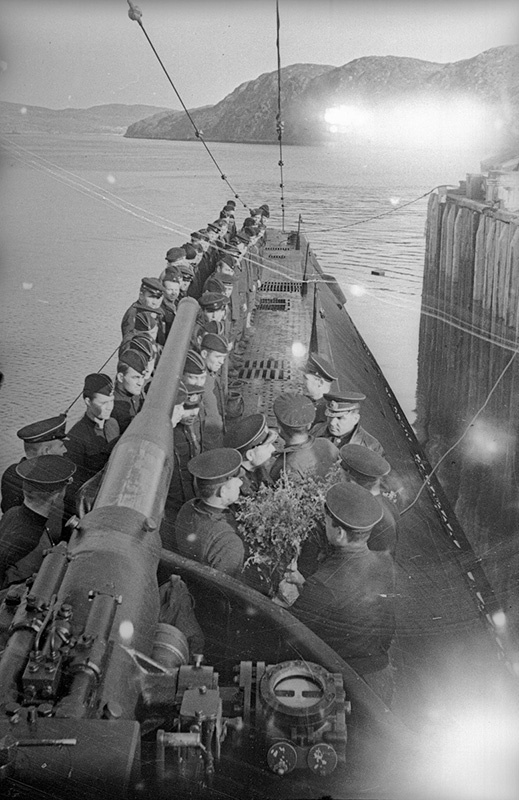 Подводная лодка «К-21» под командованием Николая Лунина после выполнения боевого задания. Северный флот, 23 августа 1942, Кольский залив. В походе советская лодка торпедировала немецкий линкор «Тирпиц». В июле 1942 года немецкое командование планировало использовать линкор «Тирпиц», броненосец «Адмирал Шеер» и тяжелый крейсер «Адмирал Хиппер» совместно с эсминцами и миноносцами для атаки конвоя PQ-17. Из-за задержек с разрешением на начало операции&nbsp; выход в море состоялся лишь 5 июля. В день выхода из передового пункта дислокации в Вестфьорде линкор был атакован советской подводной лодкой К-21. Экипаж лодки результата своей торпедной атаки непосредственно не наблюдал, однако слышал два сильных взрыва и серию взрывов слабее. Лунин в своем докладе предположил, что взрывы объясняются попаданием торпед в линкор, одновременно допуская вероятность того, что торпеды попали в один из эсминцев эскорта.Выставка «Гидроавиация и подводный флот времен Великой Отечественной» с этой фотографией.&nbsp;
