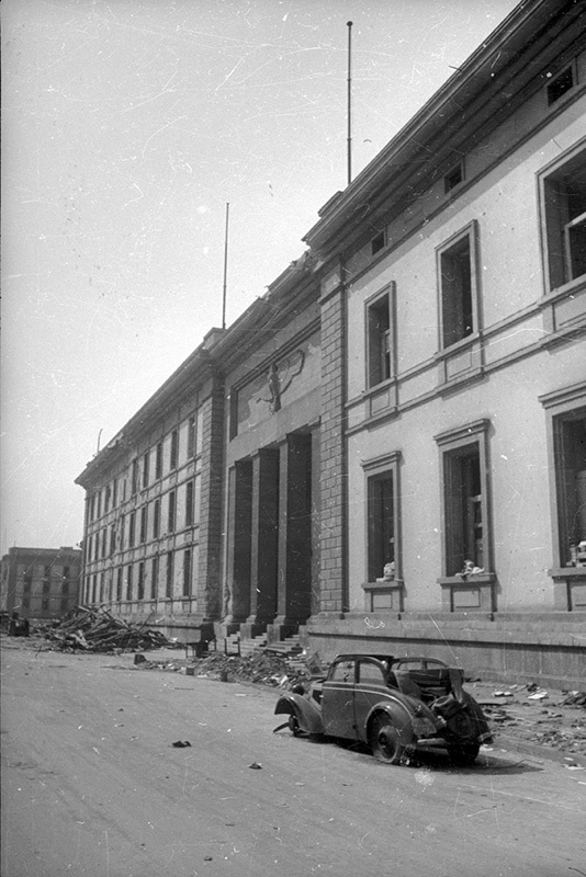 Рейхсканцелярия, 2 - 31 мая 1945, Германия, г. Берлин. В 1938 году Гитлер поручил архитектору Альберту Шпееру спроектировать здание новой рейхсканцелярии. Строительство нового здания заняло очень мало времени. Примерно через год оно было полностью готово.
В 1943 году в саду рейхсканцелярии был сооружен подземный бункер для Гитлера, так называемый Фюрербункер.
В апреле-мае 1945 года, во время битвы за Берлин, здание было сильно повреждено. После окончания войны руины рейхсканцелярии были полностью уничтожены по приказу советского командования.