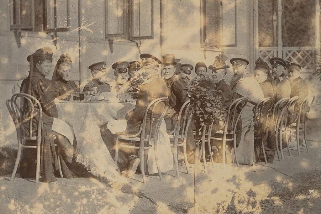 Застолье с императрицей Марией Федоровной, 1899 год. Мария Федоровна во главе стола, смотрит в камеру. Она носит траур по своей матери королеве Дании Луизе Гессен-Кассельской. Первый справа – Великий князь Георгий Александрович.&nbsp;