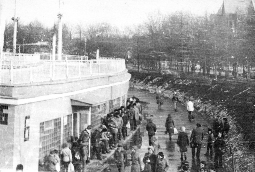 Очередь в один из секторов бассейна «Москва», апрель 1979, г. Москва. «Билеты продавались в порядке живой очереди, перед началом сеанса. Если билетов на данный сеанс не хватило, надо было гулять 45 минут до начала следующего. Секторы были мужские и женские - на фото очередь в мужской сектор, стоят одни мужчины. Потом, уже в воде, все встречались и плавали вместе».