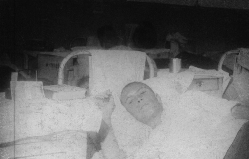 В госпитале, 1944 год. Здесь моему деду Николаеву Борису Федоровичу 18 лет, он лежит в госпитале после тяжелого ранения, раны заживали плохо, поэтому находился там долго. Был ранен в бою при освобождении Нарвы за день до своего восемнадцатилетия. Пулеметная очередь прошла через всю спину. В полевом госпитале его прооперировали, потом отправили в тыл в другой госпиталь. До этого был в партизанском отряде, позже отряд слился с действующей регулярной армией. Был пулеметчиком. Потом его комиссовали, больше не воевал.&nbsp;Фотография из архива Ольги Павловны Карелиной.