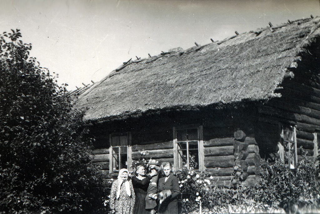 Мацково, 10 - 11 июня 1956, Псковская обл., Себежский р-н, дер. Мацково. Дом Веры Прокопьевны Дроздецкой (Гришмановской) 1912 года постройки, перенесенный после Великой Отечественной войны из другого района, поскольку вся деревня Мацково была сожжена фашистами при отступлении в 1944 году. Слева на фото – Евдокия Александровна Дроздецкая, в центре – Вера Прокопьевна Дроздецкая (Гришмановская), справа – Инна Петровна Курамшина (Дроздецкая). На руках – Вячеслав Борисович Курамшин.