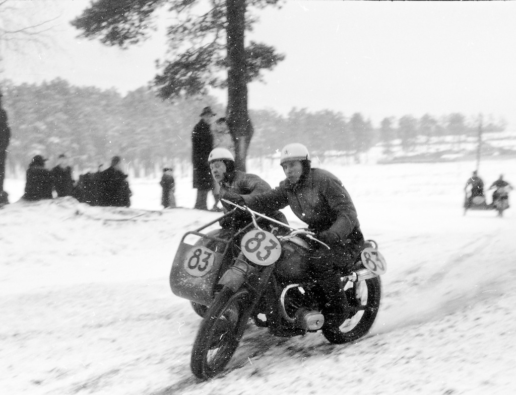 На трассе мотокросса водитель А. Е. Раутенфельд и В. Михеев, 8 января 1961, г. Москва. Зимний командный мотокросс на приз имени В. П. Чкалова состоялся 8 января 1961 года в районе Рублево.