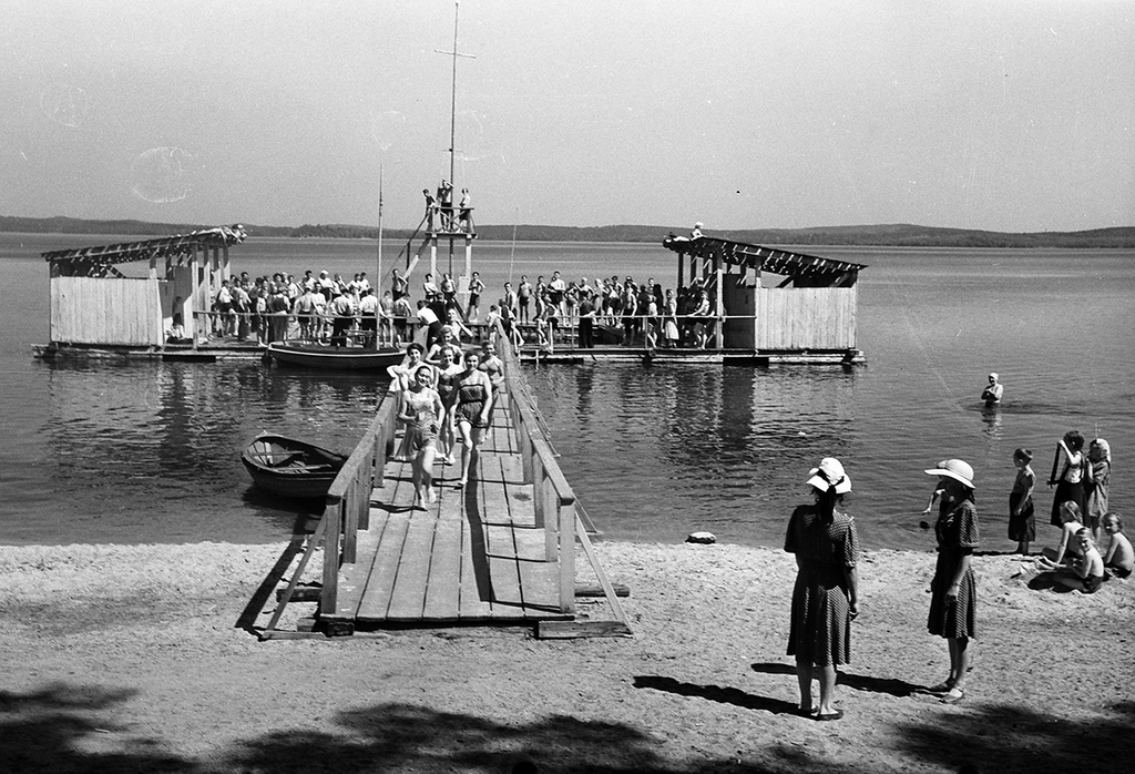 Купальня на озере, 7 июля 1953, Челябинская обл., Чебаркульский р-н. В Чебаркульском районе Челябинской области на берегу трех озер открылся Дом отдыха профсоюза угольной промышленности. В благоустроенных и светлых номерах разместилось более трехсот человек. К услугам отдыхающих: библиотека, кинозал, спортивные площадки, купальни, лодочная станция, рыбалка.