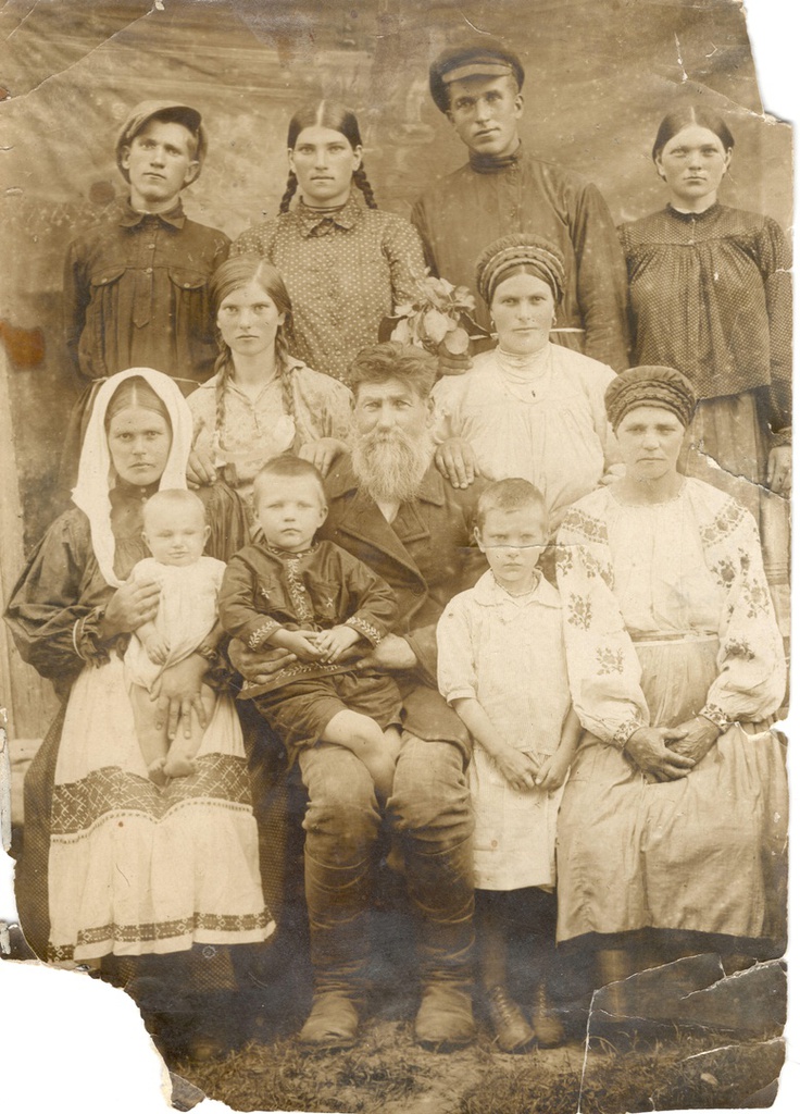 Семья Поляковых. 30-е годы, апрель - сентябрь 1933, Белорусская ССР, Костюковичский р-н, дер. Гавриленка. Мужчина с бородой и женщина справа от него – Иван Андреевич и Наталья Поляковы, мои прапрадед и прапрабабушка. Чета Поляковых окружена своими дочерьми с их мужьями и детьми. Женщина сверху между Иваном и Натальей – их вторая дочь, моя прабабушка Анна. Мальчик на руках у деда Ивана коротко стриженная девочка, которая стоит между Иваном и Натальей – старшие брат и сестра моей бабушки Иван и Татьяна.В 1938 году Костюковичский район был включен в состав Могилевской области.Фотография из архива Владислава Сергеевича Веремеенко.