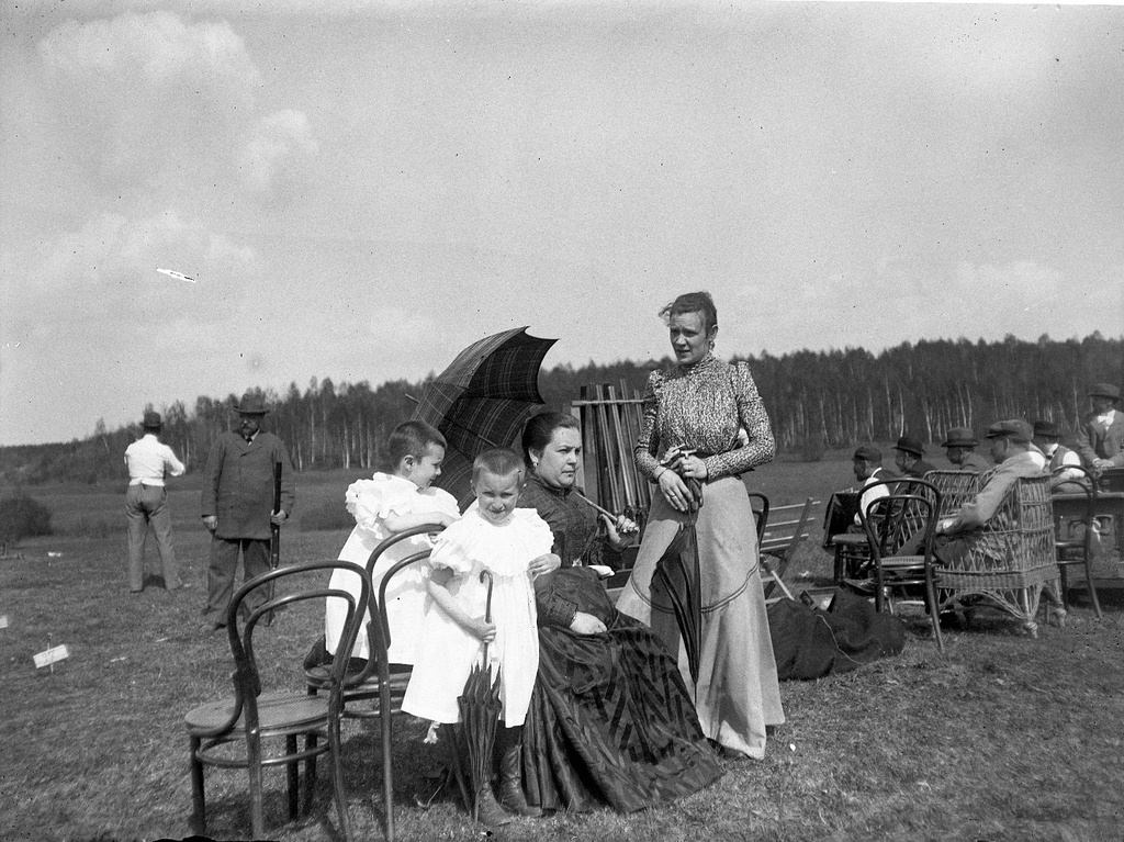 Екатерина Георгиевна Болдырева, Катя и Надя Болдыревы на стрельбах, 9 мая 1899, Московская губ., пос. Химкинская станция (станция Николаевской железной дороги). Вдали Николай Петрович Силин. Комментарий Александра Живаго: «Гостеприимная хозяка на стенде».