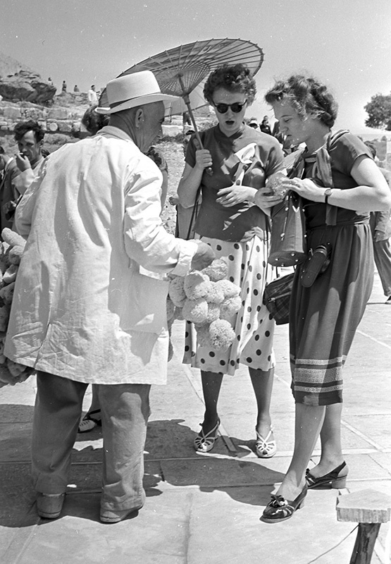 Советские туристки и продавец губок, 7 июля 1957, Греция, г. Афины. Из цикла «Вокруг Европы на теплоходе "Грузия"».Выставка «Мода в СССР: летние платья 1950–1970-х» с этой фотографией.