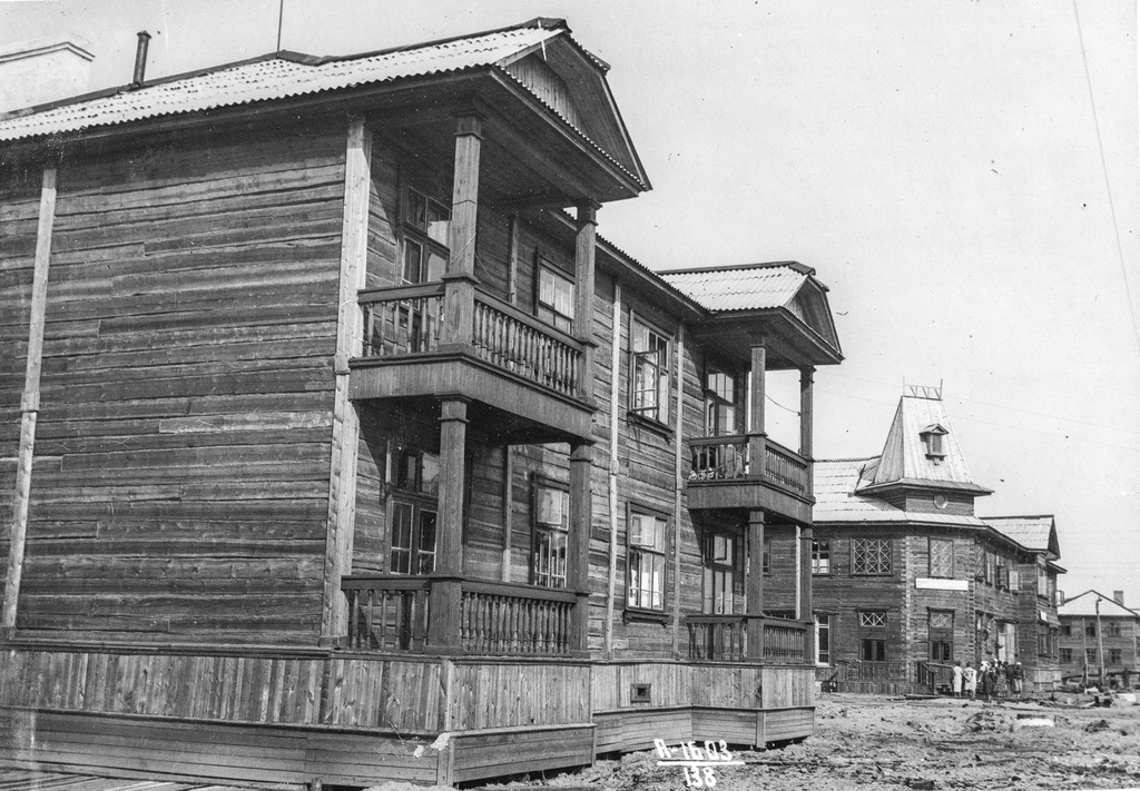 Квартал жилых домов, 13 июля 1940, Архангельская обл., г. Молотовск. Идет строительство улиц Полярная – Республиканская. Сланевые дороги еще не проложили, территория вокруг домов не благоустроена. На перекрестке узнаваем дом с высокой башенкой на крыше. В подобных домах размещались магазины.Город Молотовск в 1957 году переименован в Северодвинск. 