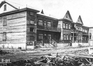 Жилой дом на 4 участке, 23 сентября 1938, Архангельская обл., г. Молотовск. Вид на деревянный двухэтажный жилой дом с несколькими подъездами и  длинными балконами-галереями на первом  и втором этажах. Территория около дома не благоустроена. Вокруг – стройматериалы и строительный мусор.Рабочий поселок Судострой в 1938 году получил статус города и название Молотовск. В 1957 году переименован в Северодвинск. 