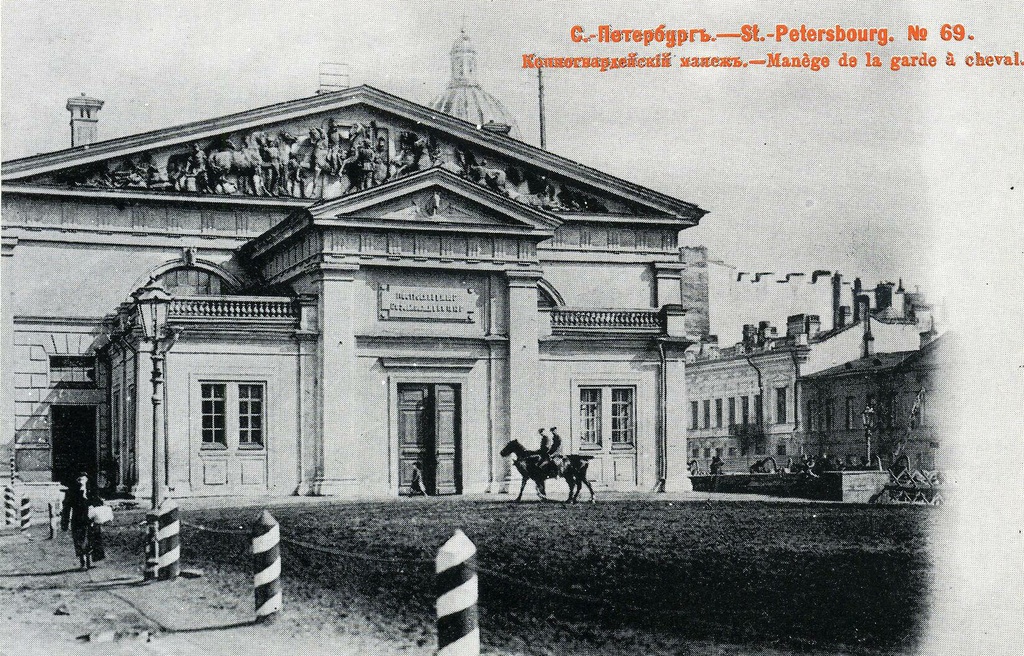 Конногвардейский манеж (№ 69), май - июнь 1903, г. Санкт-Петербург. В мае – июне 1903 года, в дни празднования 200-летия Петербурга, журнал «Родина» заказал фотографу Н. Н. Ольшевскому снимки для юбилейного очерка. Эти фотографии издательство и выпустило в виде серии из 100 нумерованных открыток. Все снимки сделаны в небольшой промежуток времени и дают «срез» жизни города.Ольшевский решает свою задачу неординарно: смело вводит в кадр живые бытовые детали, уличные сцены, типы городских жителей. Снимая архитектуру, он ищет неожиданный ракурс, фотографирует недостроенные здания – ведь «строительный бум» один из характернейших признаков петербургской жизни того времени.Открытки для издания любезно предоставил ленинградский коллекционер Н. П. Шмитт-Фогелевич.Выпуск № 1 «Образы старого Петербурга» издательства «Ленинградское отделение Советского фонда культуры», 1989 год, заказ № 3176 от 05.05.1990 год. Составители серии: А. В. Кобак, Т. Б. Притыкина, Н. П. Шмитт-Фогелевич.№ 69 – «Конногвардейский манеж».Манеж  лейб-гвардии Конного полка был построен в  1804–1817 годах архитектором  Джакомо Кваренги вблизи комплекса  полковых  казарм  на  Конногвардейском  бульваре. На открытке хорошо виден терракотовый барельеф в тимпане работы скульптора Д. И. Иенсена, изображающий  занятия конногвардейцев на манеже. Он был установлен в 1872–1873 годах, во время перестройки здания по проекту профессора Д. И. Гримма. Тогда же к заднему фасаду пристроили вестибюль, разобранный в конце 1970-х годов.