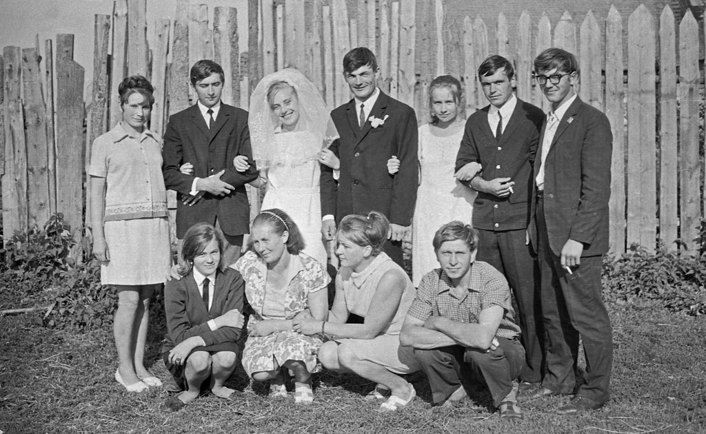 Свадебное групповое фото, июнь 1970, Калининская обл., Старицкий р-н, д. Орешки. Александр Александрович Кружков проработал шофером более 40 лет в деревне Турково в Калининской, а затем в Тверской области. Все это время верными друзьями Александра Александровича были гармонь и фотокамера. В сельской глубинке владение этими вещами автоматически делало его первым парнем на деревне. Где с гармонью, как главное действующее лицо, где с фотокамерой, как внимательный летописец деревенских хроник, Александр Александрович принимал активнейшее участие в культурной жизни односельчан.  А событий в деревне хватало. Тут и свадьбы, и празднования дня Победы 9 мая, и сенокосы, и уборка картофеля, и день знаний 1-го сентября, и проводы в армию, и даже похороны…  Сейчас Александр Александрович уже не снимает. Пришла очередь детей и внуков. Лишь изредка берет в руки гармонь. Представлены серии снимков, сделанных Александром Александровичем в Калининской области с начала 70х годов до конца 90х годов прошлого века.