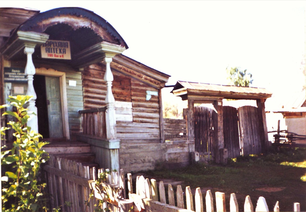 Семиречье. Лепсинск, 1990 год, Казахская ССР, Талды-Курганская обл., Саркандский р-н, с. Лепсинск. На снимке изображен типичный сибирский казачий дом в Лепсинске (расположен в городской его части), представляющий из себя деревянное жилое строение, с высоким крыльцом с козырьком и нишею, которое характерно именно для Семиречья, мы видим также деревянные ворота на каменных столбах (в настоящее время ворота не сохранились). В поздние советские времена здание использовалось под аптеку, сейчас действует как гостиница.Выставка «Аптеки ХХ века» с этой фотографией.