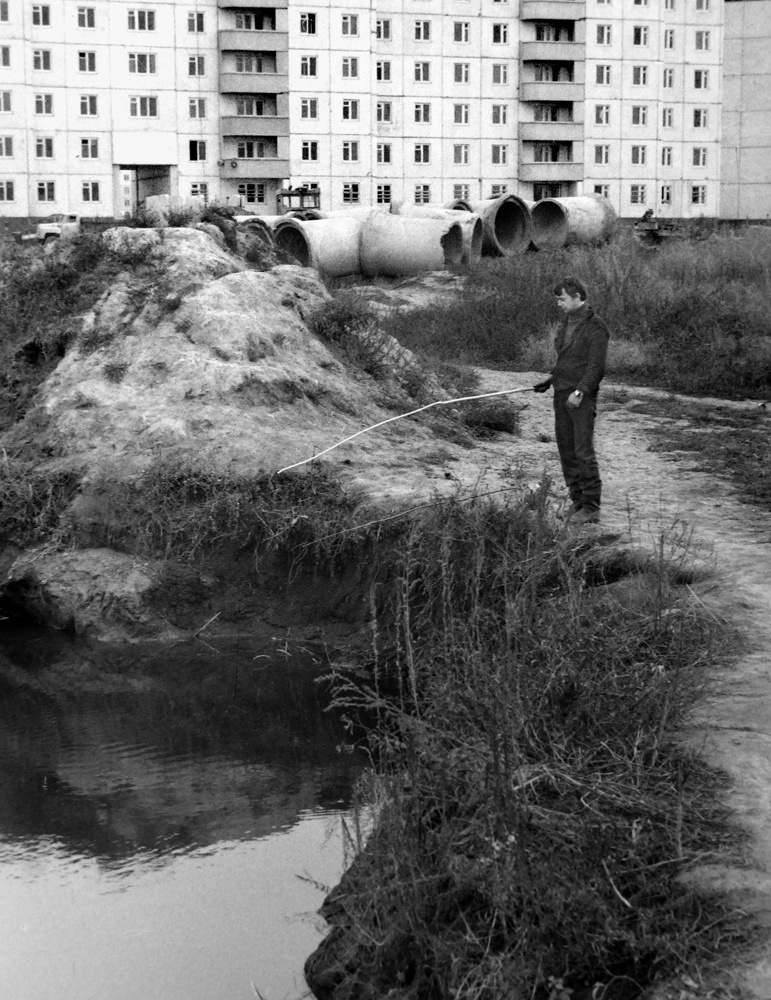 «Раннее утро на объекте». Юго-Западный жилмассив. Котлован, октябрь 1985, г. Новосибирск. В строительных бригадах были, естественно, и рыболовы. Они иногда приезжали на объект пораньше, до начала рабочей смены – «потестировать поплавки». Клевали чебачки, окуньки, карасики. Рыбу тут же солили, потом вялили.Видео «Клюет!» и выставка «В Новосибирске Сергея Секретарева» с этой фотографией.