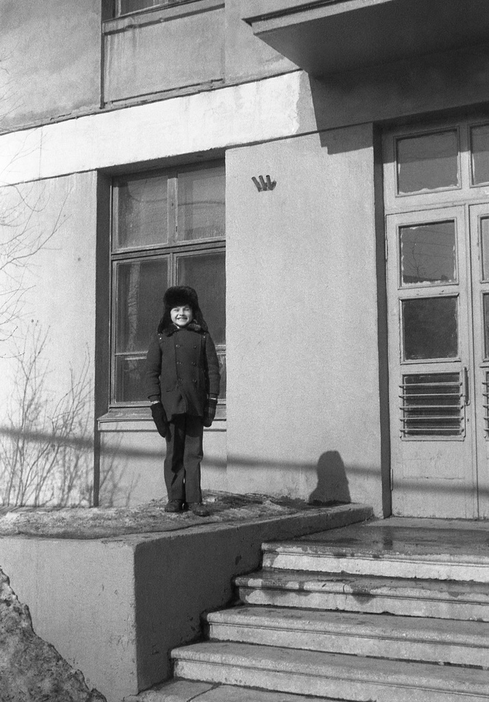 Школа № 301 в Свиблово, март 1977, г. Москва. Выпускной 8 класс «В» стоит внизу лестницы за кадром, все собрались для поездки куда-то в центр Москвы на экскурсию. Второклассник Максим Михайловский, сын классного руководителя 8 класса «В», едет вместе со всеми. Справа – вход в школу № 301. Камера «Смена 8».