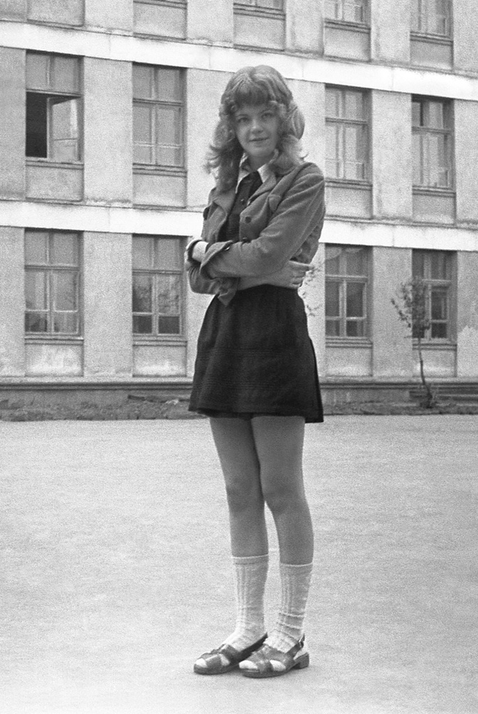 Школа № 301 в Свиблово, 8 класс «В», май 1977, г. Москва. Большая перемена. Девочка из 8 класса «В» на задней площадке школы № 301 на ул. Седова. Съемка «скрытой камерой» – фотоаппарат без чехла прятался в расстегнутую школьную куртку, в нужный момент фиксировался на животе и нажимался спуск. Поэтому точка съемки ниже лица. Предварительно выставлялась нужная глубина резкости. Камера «Смена 8».