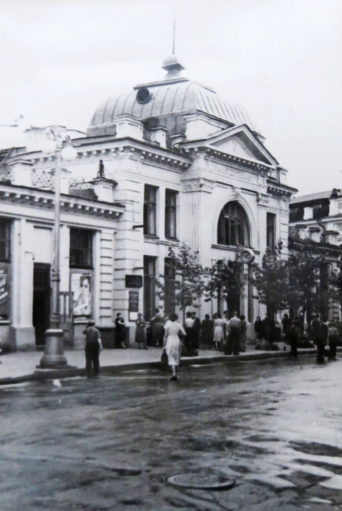 Кинотеатр Художественный, 1956 - 1958, г. Иркутск. Здание перестроено из находившегося на этом месте театра «Фарс», оно занимает весь небольшой квартал по Большой улице (ныне Карла Маркса) между 1-й и 2-й Солдатскими улицами (Красноармейской и Лапина). Дом был арендован у И. Е. и С. Е. Замятиных турецким подданным К.С. Ягджоглу, открывшим кинематограф. В зрительном зале немецким профессором живописи Энгелем в 1912 был расписан плафон на мифологическую тему. В 1912 при театре был открыт скейтинг-ринг (существовал также ресторан с названием «Скейт-Ринг»).  В январе 1917 года кинематограф К.С. Ягджоглу был куплен его конкурентом А.М. Дон-Отелло за 10 тыс. руб.В 1920–1930-е годы Советская власть национализировала в стране все прежние кинематографические заведения, часть из которых прекратила свое существование. Дон-Отелло, лишенный всего имущества, покинул Россию и увёз с собой в Харбин своё творческое наследие, безвозвратно растворившееся в водовороте войн и революций. Многие здания и помещения, служившие ранее залами для демонстрации фильмов, были отданы под хозяйственные нужды государственным учреждениям, в сохранившихся помещениях открылись кинотеатры с новыми названиями: иллюзионы «Дон-Отелло» на Большой улице переименовали в «Хронику» и «Гигант», а «Декаданс» К.С. Ягджоглу – в «Художественный».
