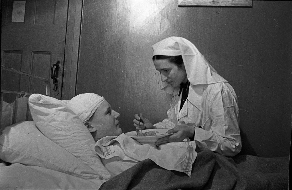 Сестра Козлова кормит тяжелораненого, 1943 - 1945. Выставка «Военные фотографии Елизаветы Микулиной» с этим снимком.
