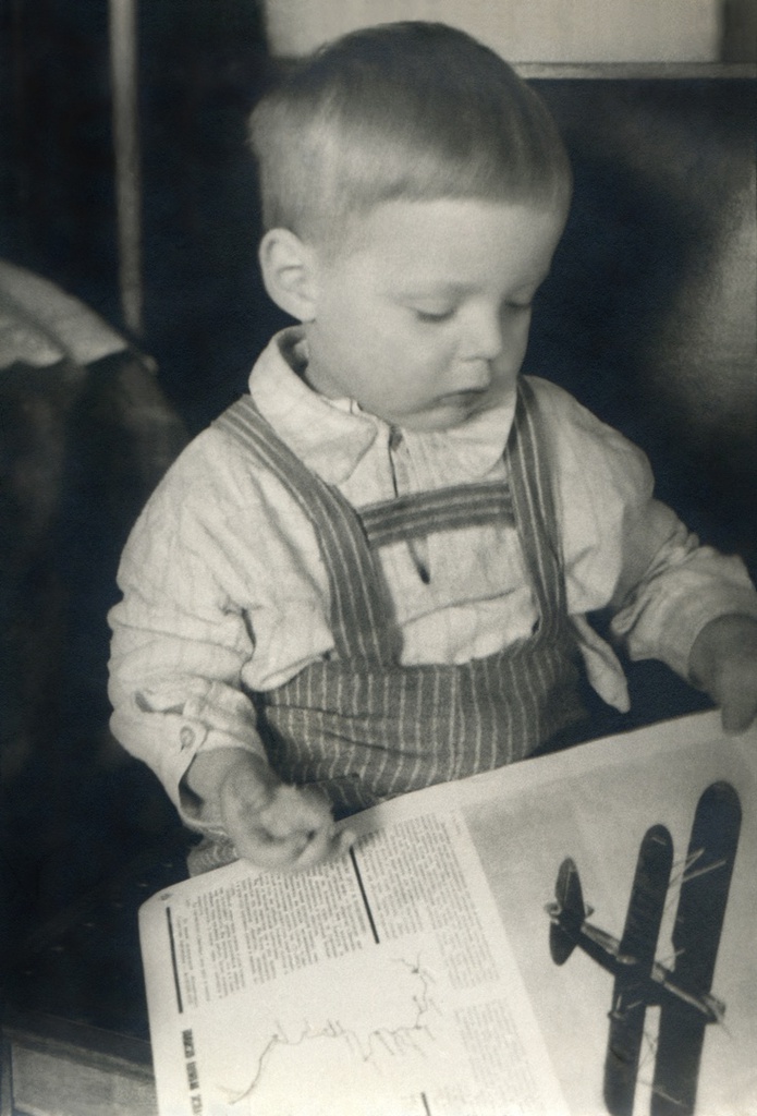Портрет сына с журналом в комнате, 1935 год, г. Москва. Комната на верхнем этаже в коммунальной квартире, метров 15-20, где жил автор с женой, сыном и тещей. Автор – Борис Александрович Баш (Шишлянников) (1901–1942), фотограф, кинооператор и режиссер.