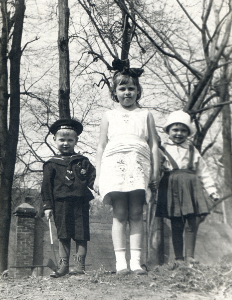 Портрет сына (слева) и соседских девочек на клумбе, во дворе дома, 1936 год, г. Москва. Огороженный двор старого дома 10 на Житной улице, где жила семья автора. Виден забор и слева, за забором, видна часть дома 3с6 по 2-у Спасоналивковскому переулку (нумерация современная). Автор – Борис Александрович Баш (Шишлянников) (1901–1942), фотограф, кинооператор и режиссер.