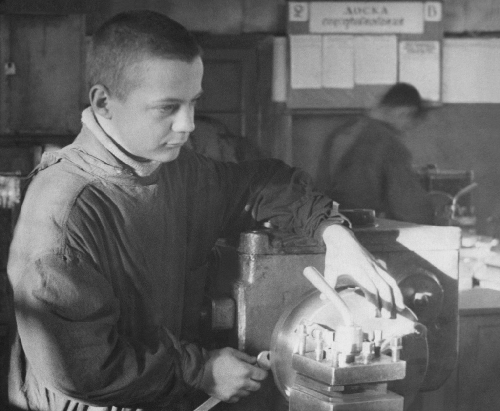 Олег Борисович Баш за токарным станком в производственных мастерских Ремесленного училища № 57, 1946 - 1947, г. Москва. На стене виден стенд, то ли класса, то ли группы: 2 «В». Доска (чего-то там). Специализация Ремесленного училища № 57 – слесари инструментальщики, сборщики часовых механизмов и токари-универсалы. Училище располагалось на Малой Ордынке, дом 13, потом преобразовалось в СПТУ № 15. Точка съемки выставлена условно.