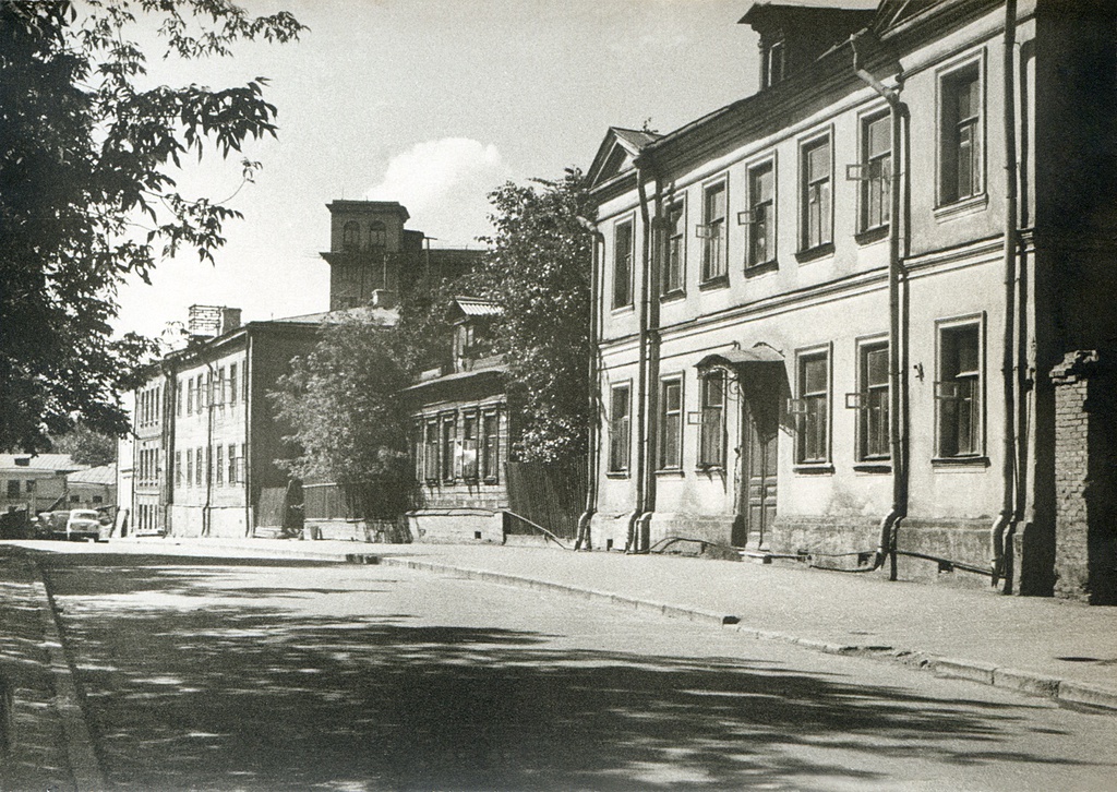 Волков переулок, дома № 5, 7 и 9, 1961 - 1963, г. Москва. По Волкову переулку: дом № 5 (двухэтажный, слева), дом № 7 (деревянный одноэтажный, где в коммунальной комнате жил автор с женой, сыном и родителями жены) и дом № 9 (двухэтажный, ближний справа). Слева видны дома на улице Красная Пресня (на выезде из Волкова переулка – снесены) и башня на доме 9 по ул. Красная Пресня (дом стоит до сих пор). В 1962 часть старой Пресни стали ломать и застраивать новыми домами. Дома № 5, 7 и 9 в Волковом переулке пошли под снос в 1964 году, сейчас на месте 7-го дома проезд во дворы.