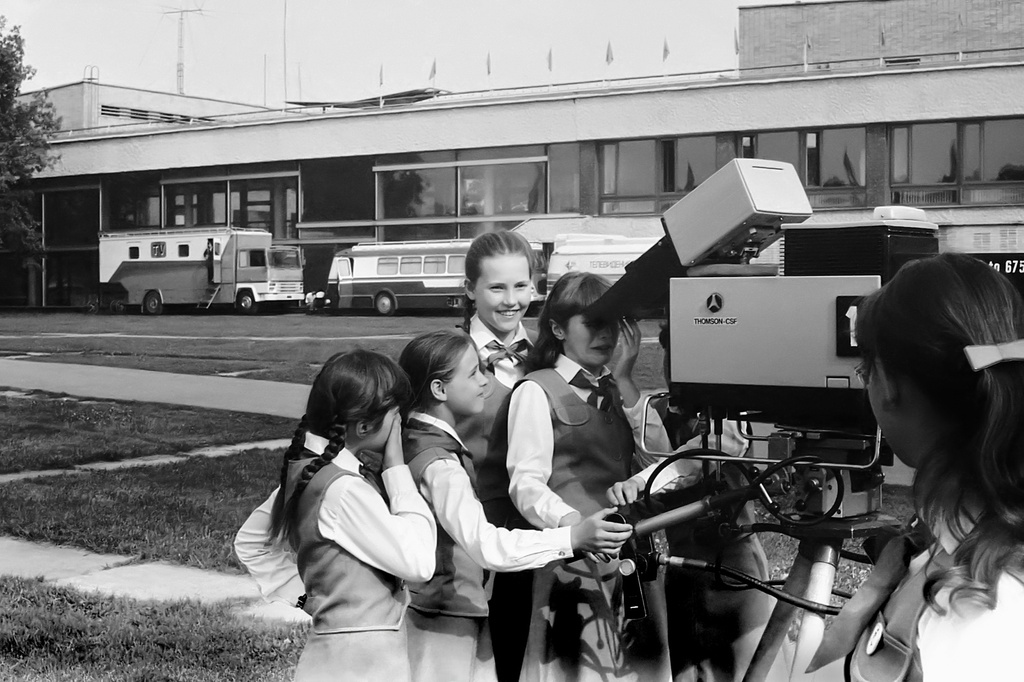 Дворец пионеров на Ленинских горах. Выступление ансамбля имени В. С. Локтева, 1983 год, г. Москва. Запись выступления хора. Перерыв. Участники ансамбля у телекамеры Thomson CSF TTV 1515. Позади видна спецтехника телецентра «Останкино» у здания Дворца пионеров: слева – ПТС (передвижная телестанция) на шасси Berliet GR 260, правее – автобус Škoda 706 RTO. Концертный зал справа за кадром.