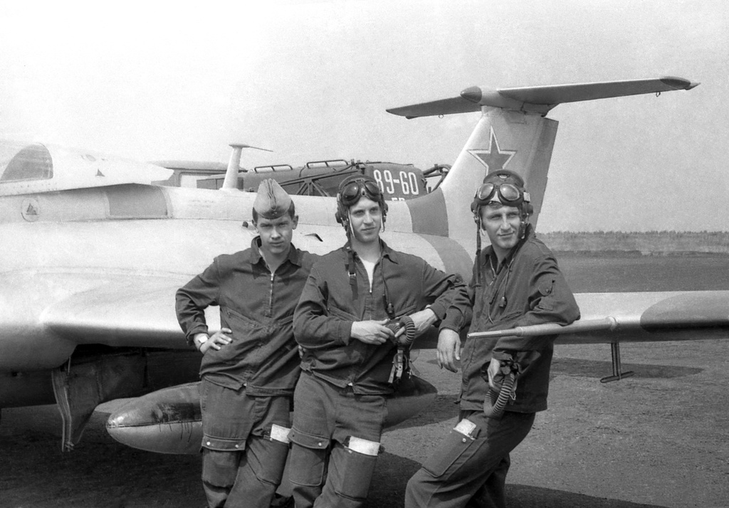 Полеты на грунтовом аэродроме в Кирсанове, 643 уап ТВВАУЛ, июнь - август 1982, Тамбовская обл., Кирсановский муниципальный округ, Голынщинский сельсовет. Курсанты ТВВАУЛ на стоянке самолетов Л-29. Позади видна АПАшка.643 учебный авиаполк ТВВАУЛ (в/ч 42149, база: город Тула, аэродром Клоково, самолеты Л-29). На лето авиаполк перелетал из Тулы в Кирсанов и Новгородовку Тамбовской области (по две эскадрильи на каждый город).ТВВАУЛ – Тамбовское высшее военное авиационное училище летчиков имени М. М. Расковой.Часть расформирована в 1990 году, потом в 1995 году закрыли и Тамбовское ВВАУЛ.АПАшка (жен. род, сленг летчиков и техсостава): АПА-5Д, Аэродромный Передвижной электроАгрегат, на базе Урал-4320 (на фото), является автономным источником электрической энергии и предназначен для одиночного и группового электростартерного запуска авиационных двигателей, питания бортовой электроаппаратуры самолетов в наземных условиях, а также для буксировки самолетов.