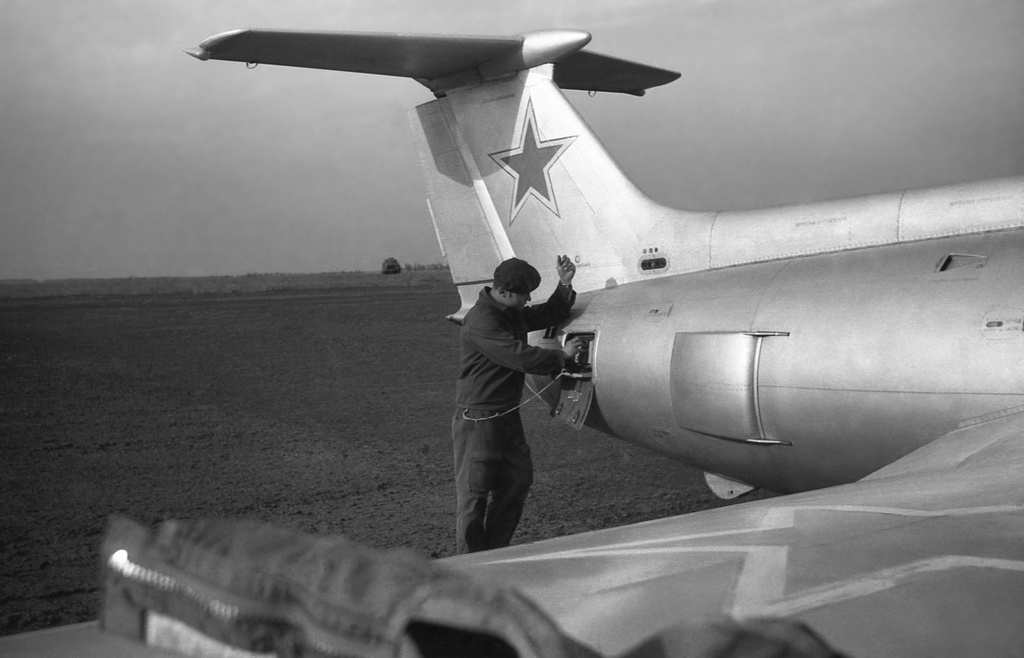 Полеты на грунтовом аэродроме в Кирсанове, 643 уап ТВВАУЛ, июнь - август 1982, Тамбовская обл., Кирсановский муниципальный округ, Голынщинский сельсовет. АОшник 1-й эскадрильи Вадим Баш (срочник) прописывает «нули» на чистой пленке в кассете для САРПП-12 перед вылетом самолёта Л-29.643 учебный авиаполк ТВВАУЛ (в/ч 42149, база: город Тула, аэродром Клоково, самолеты Л-29). На лето авиаполк перелетал из Тулы в Кирсанов и Новгородовку Тамбовской области (по две эскадрильи на каждый город).ТВВАУЛ – Тамбовское высшее военное авиационное училище летчиков имени М. М. Расковой.Часть расформирована в 1990 году, потом в 1995 году закрыли и Тамбовское ВВАУЛ.САРПП-12 – система автоматической регистрации параметров полета. Запись параметров ведется на фотопленку в металлической кассете. После полета кассету с записью снимали и заменяли на новую, с чистой пленкой.АОшник (сленг) – техник группы АО (авиационного оборудования), специалист, отвечающий за исправность электрических и приборных систем воздушного судна.