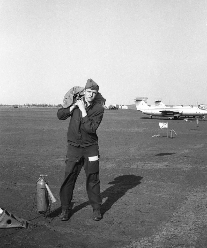 Полеты на грунтовом аэродроме в Кирсанове, 643 уап ТВВАУЛ, июнь - август 1982, Тамбовская обл., Кирсановский муниципальный округ, Голынщинский сельсовет. Курсант ТВВАУЛ Павел Пикулев с парашютом на плече на грунтовой стоянке самолетов Л-29.643 учебный авиаполк ТВВАУЛ (в/ч 42149, база: город Тула, аэродром Клоково, самолеты Л-29). На лето авиаполк перелетал из Тулы в Кирсанов и Новгородовку Тамбовской области (по две эскадрильи на каждый город).ТВВАУЛ – Тамбовское высшее военное авиационное училище летчиков имени М. М. Расковой.Часть расформирована в 1990 году, потом в 1995 году закрыли и Тамбовское ВВАУЛ.