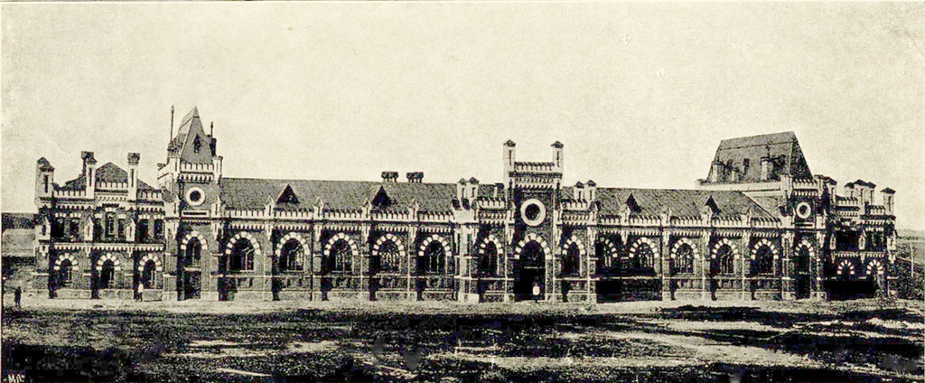 Конезавод Фон Дервиза, 1900 - 1910, Рязанская губ., Пронский у., с. Старожилово. Своим возникновением Старожиловский конный завод напрямую обязан Рязанско-Козловской железной дороге. Павел Григорьевич фон Дервиз, предприниматель и меценат, в марте 1865 года, совместно с инженером К. Ф. фон Мекком, получил концессию  на ее строительство. Схема финансирования была новаторской для России, и дорога была построена менее, чем за 1,5 года. За короткий срок фон Дервиз получил такие дивиденды, что стал одним из самых богатых людей России. В Пронском уезде Рязанской губернии дорога проходила вблизи села Старожилово, и Павел Григорьевич выкупил 3 000 десятин земли у местных помещиков – кн. Орлова и г-на Каншина для своего поместья, строительство которого было поручено архитектору Д. И. Гримму. Но поместье оказалось убыточным, и П. П. фон Дервиз остановил стройку, а имение подарил своему брату, после смерти которого оно перешло к младшему сыну Павла Григорьевича – Павлу Павловичу. Именно с именем Павла Павловича связано начало расцвета коневодства в Старожилове. Еще будучи на службе, он развернул в Старожилове строительство, и с 1891 по 1897 гг. на территории около 15 га появился комплекс из 12 сооружений из красного кирпича, в числе которых в 1893 г. был построен и конный завод, архитектор которого до сих пор достоверно не известен.
