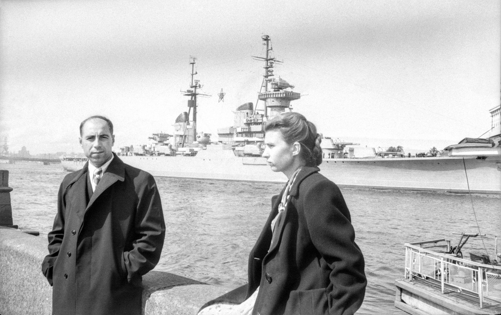 На набережной Невы, 1 - 28 июля 1956, г. Ленинград. Михаил Трофимович Кретинин и Клавдия Федоровна&nbsp;Иванова на набережной.&nbsp;На Неве крейсер «Жданов» готовится к празднованию Дня ВМФ. Легкий крейсер проекта 68-бис, заводской номер 419. Построен на Балтийском заводе в Ленинграде (ранее завод № 189 имени Серго Орджоникизде). 29 июля 1956 года этот крейсер (бортовой № 20) участвовал в параде по случаю ДНЯ ВМФ в качестве флагманского корабля. На его борту главком ВМФ СССР адмирал Сергей Георгиевич Горшков выступил с речью.Пленка № 010, кадр 11 © Г. В. Иванов.