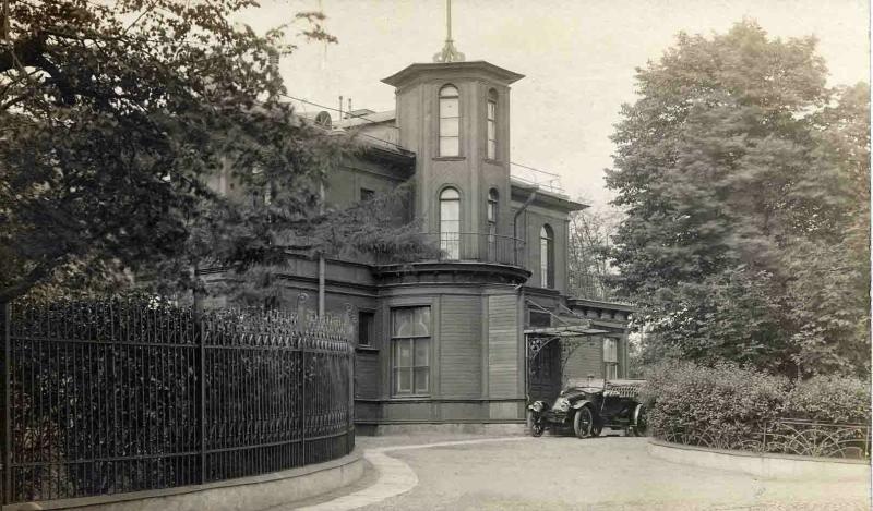 Деревянное здание с башней на фасаде, 1910-е, г. Санкт-Петербург. Особняк Шарлье (Розенкранца) на Свердловской (до 1925 года Полюстровской) набережной, дом 12, построен в XVIII веке, перестроен в 1849 году для бельгийского консула Ивана Августовича Шарлье - управляющего на заводе Розенкранца. В советское время в нем располагались клуб и музей завода «Красный Выборжец». Сейчас здание пустует.