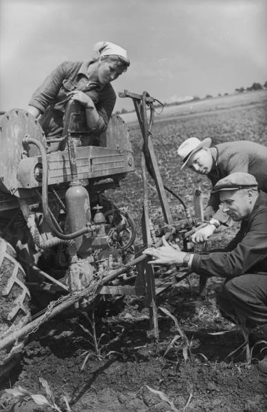 Ремонт сельскохозяйственного агрегата, 1955 - 1965. Двое мужчин осматривают сельскохозяйственный аппарат для впрыскивания удобрений в почву.