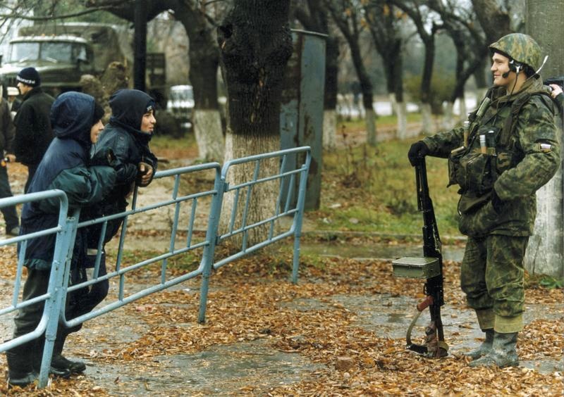 Незапланированные переговоры, 13 ноября 1999, Чеченская Республика, г. Гудермес. Солдат группировки федеральных сил и чеченские мальчишки на улицах Гудермеса после освобождения его от бандформирований.7 августа 1999 года началась Вторая чеченская война. Активная фаза боевых действий продолжалась с 1999 года по 2000 год.