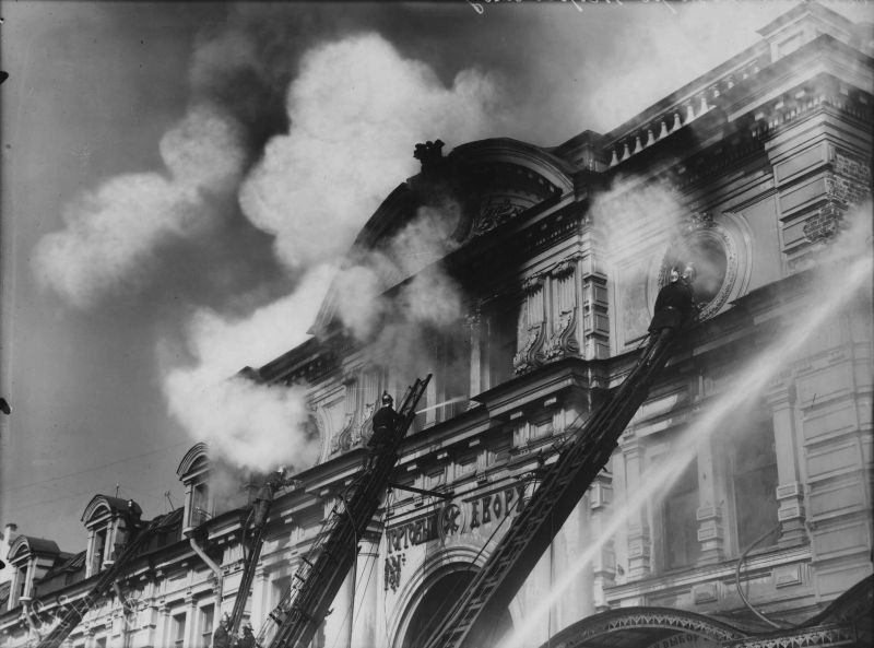 Пожарные на лестнице у дымящейся крыши Апраксина двора, 3 июля 1914, г. Санкт-Петербург. Выставка «Накануне» с этой фотографией.