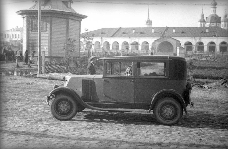 Автомобиль на дороге, 1929 год, г. Вышний Волочек. Из серии «Поездка в Ленинград на автомобиле "Рено" Маяковского». На заднем плане — торговые ряды и Казанский собор (утрачен в 1935 году).