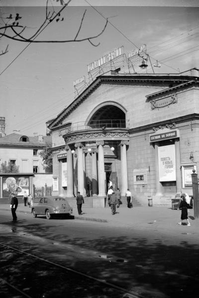 Кинотеатр «Колизей», 1950-е, г. Москва. На фасаде – рекламные плакаты фильмов «Повесть о новых героях», «Смелые люди», «Тринадцать». У тротуара стоит легковая машина «Победа».