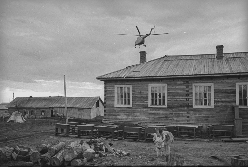 Парты перед школой и вертолет, 1965 год, Архангельская обл., Ненецкий НО, г. Нарьян-Мар. Из серии «Край земли. Ненцы».В 1977 году Ненецкий национальный округ был переименован в Ненецкий автономный округ.
