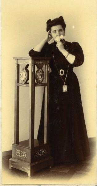 Женщина в темном платье у подставки с двумя цветами, 1907 год