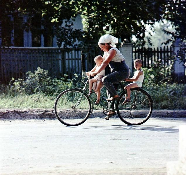 Женщина с детьми на велосипеде, 1968 год, Краснодарский край, Кореновский р-н, станица Платнировская. Выставка «На "педальном коне"»&nbsp;и видео «Пора гулять» с этой фотографией.