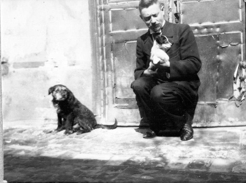 Мужчина на корточках со щенком на руках, 1910-е