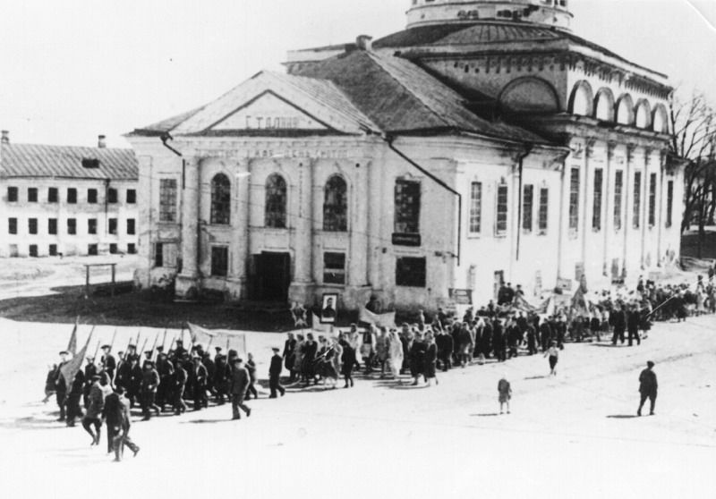 Колонна людей, движущаяся под флагами на праздничной демонстрации на фоне здания бывшей Успенской церкви, 1940-е, Нижегородская область