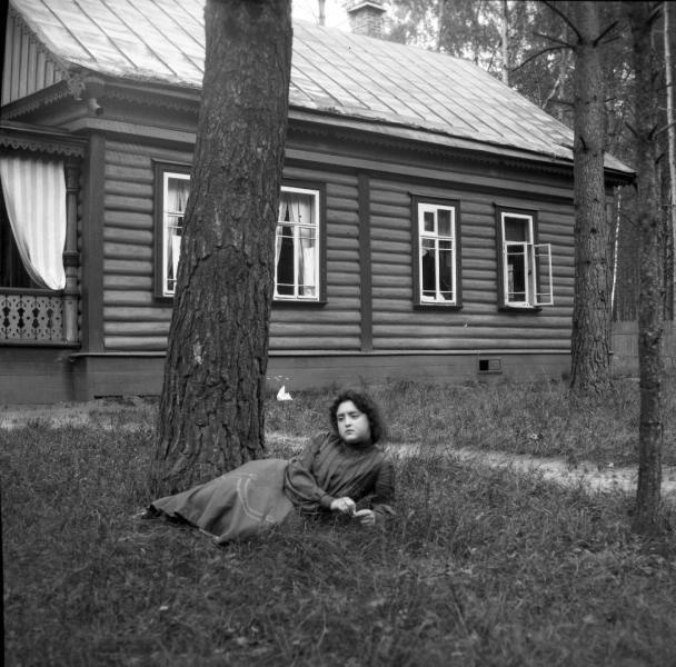 Маня лежит около дерева в саду. Позади дача, 1904 год, Московская губ., Московский у., с. Вешняково