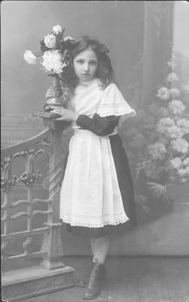 Портрет гимназистки в белом переднике с цветами, 31 декабря 1917. Выставка «Гимназистки. Из воспоминаний Веры Федоровны Пановой» с этой фотографией.