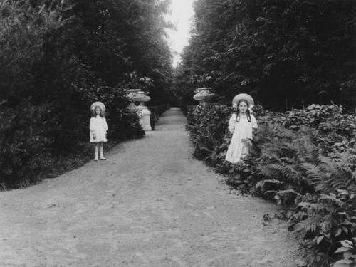 Девочки в нарядных платьях по бокам аллеи с вазами для растений, 1900-е