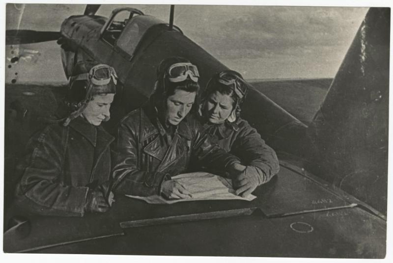 Летчицы женского 586-го истребительного авиаполка Мария Кузнецова (справа), Екатерина Буданова (в центре) и Лидия Литвяк (слева) у самолета, 1943 год. Выставка «Авиатриссы» с этой фотографией.