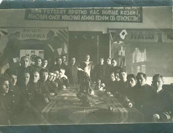 Красноармейцы за столом, 1920-е. Надпись на транспаранте: «...они готовят против нас новые козни! Красный флот, Красная Армия, помни об опасности!». Надпись на плакате слева: «Культ-смычка».